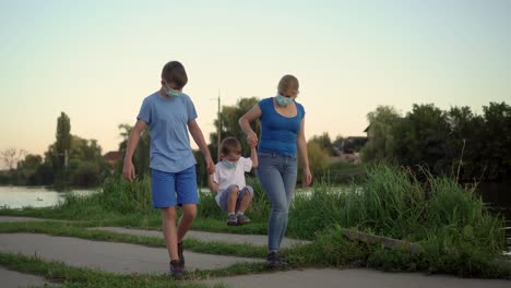 a family with a child in medical masks walk near the lake 02