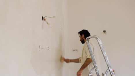 a man using large paintbrush creating brush strokes on the wall during limewash painting