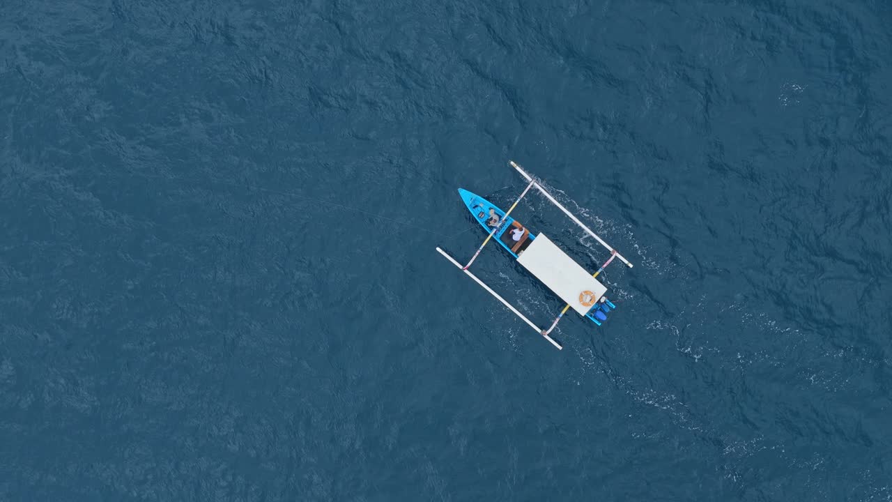 Traditionel balinesisk jukung-fiskebåd navigerer på åbent blåt hav