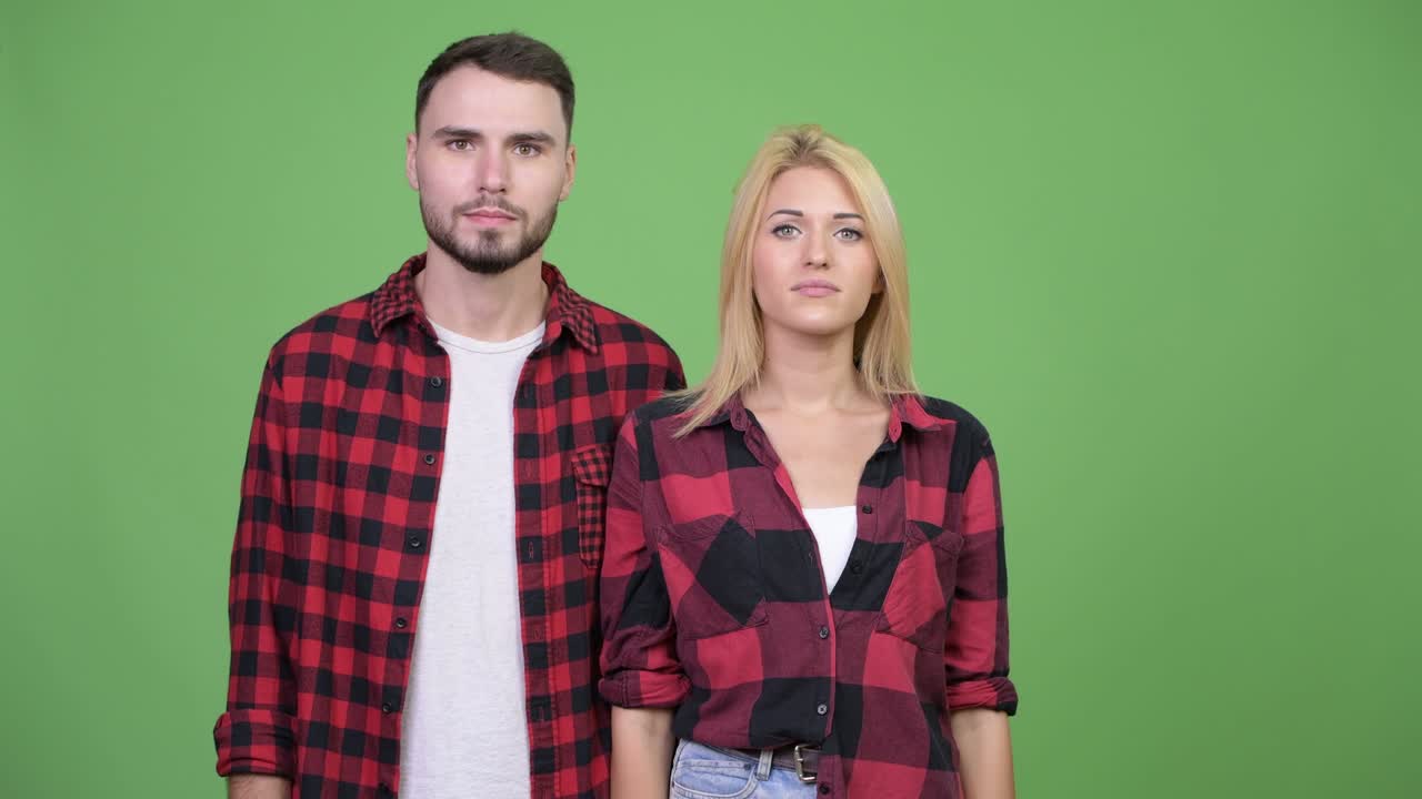 Young couple pointing finger up together