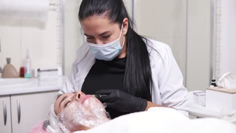 shot in 4k: professional comsetologist in mask making multiple injections in woman's cheek during mesotherapy. biorevitalization and face lifting, non-surgical medicine treatment