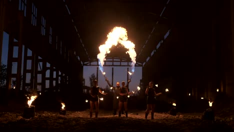 professional fire show in the old hangar of the aircraft show professional circus artists three women in leather suits and a man with two flamethrowers.