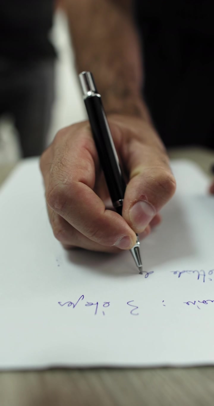 Close-up tangan menulis di kertas dengan pena, menangkap tindakan dokumentasi komunikasi dan