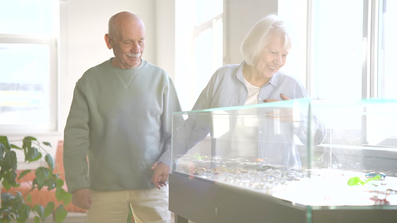 pareja mayor tomándose de la mano y mirando joyas dentro de una urna en un estudio