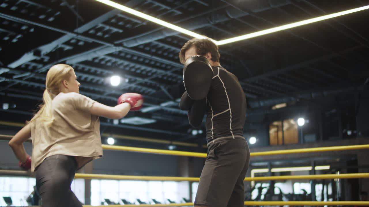 pareja deportiva ansiosa practicando golpes de piernas en el gimnasio. chica en forma entrenando en un club deportivo