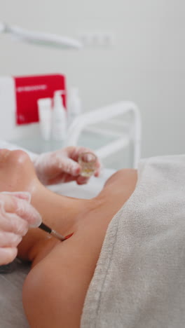 cosmetologist applying special moisturizing acid serum peeling face chest of young woman in clinic