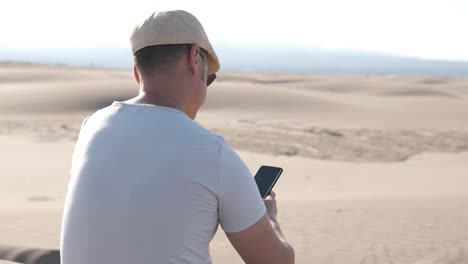 man using smart phone with internet connection in the desert dunes alone
