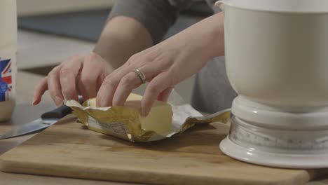 mano femenina abriendo un paquete de mantequilla