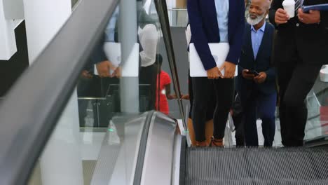 Network-of-profile-icons-against-low-section-of-businesspeople-on-escalator-at-office