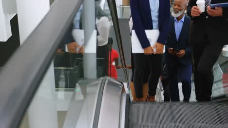 network of profile icons against low section of businesspeople on escalator at office