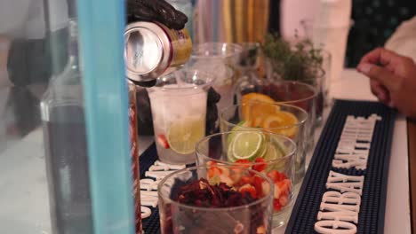 professional bartender pours soda and ice drinks into plastic glasses to prepare fruit alcohol cocktails during a party