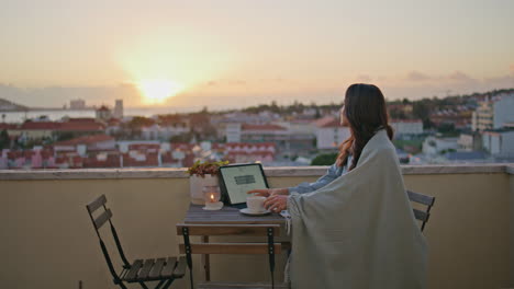 cute brunette drawing sketch in notebook at evening rooftop. woman drink coffee