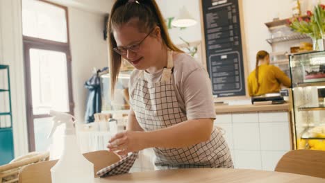 Caucasian-woman-with-down-syndrome-cleaning-table-in-the-cafe