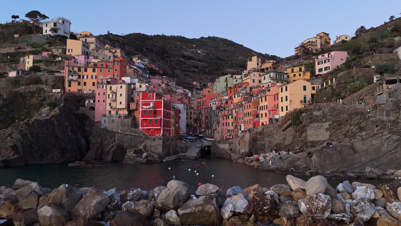 Village coloré de Riomaggiore aux Cinque Terre, falaises côtières et bâtiments aux couleurs vives.