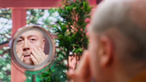 pensioner using serum and cream to preserve his mature skin with wrinkles