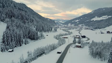 aerial shot of a snow covered mountain town, winding road through the valley