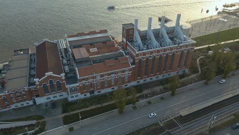 Edificio-De-Fábrica-Industrial-Cerca-Del-Río-Tajo-En-Lisboa,-Portugal,-Filmado-Con-Un-Dron-Durante-La-Puesta-De-Sol