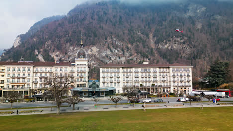 Lobby-entrance-for-famous-hotel-at-the-base-of-a-foggy-mountain-in-Interlaken-Switzerland,-aerial-pullback