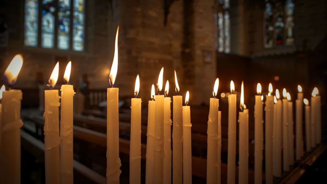 Camera focusing, taper candles burning and dripping wax on metal rack in stone church for prayer