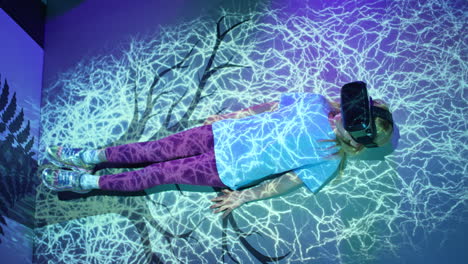 chica con gafas vr acostada en el suelo, efectos de luz fluorescentes, disparo de arriba hacia abajo