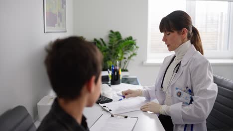doctor discussing medical records with teenager patient