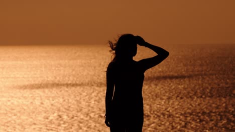 silhouette of a woman gazing over the golden sea at sunset along portugal's coast, evoking calm and reflection