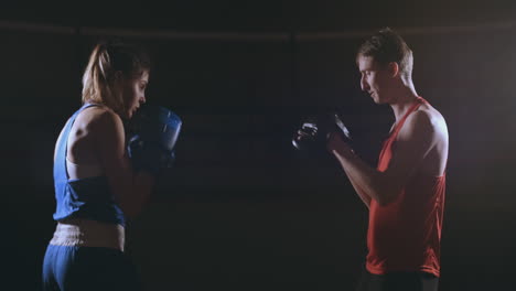 mujer golpea los guantes de enfoque en el gimnasio de boxeo