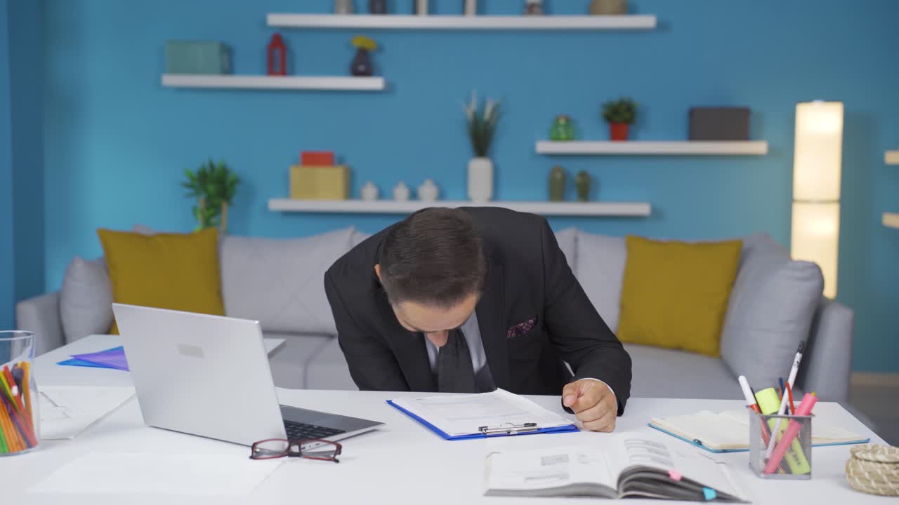 어색한 남자가 책상에 앉아 있는 동안 펜을 떨어뜨린다.