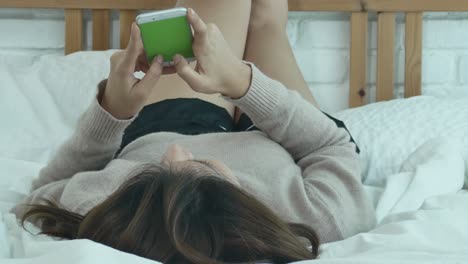 happy asian women are using smart phone on the bed in morning. asian woman in bed checking social apps with smartphone. smiling woman surfing net with cellphone at home. mobile addict concept.