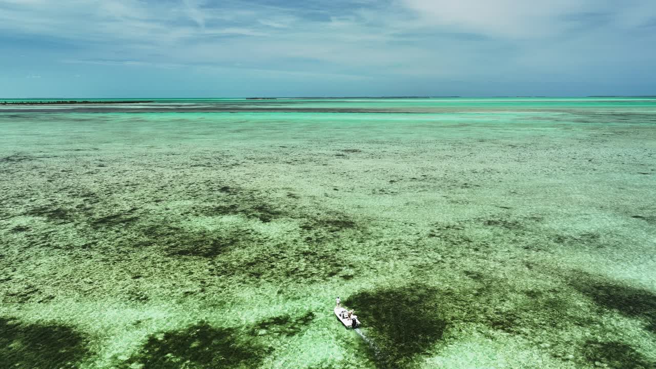 barco de pesca en movimiento lento en plano y arrecife, vista aérea desde atrás, bahamas