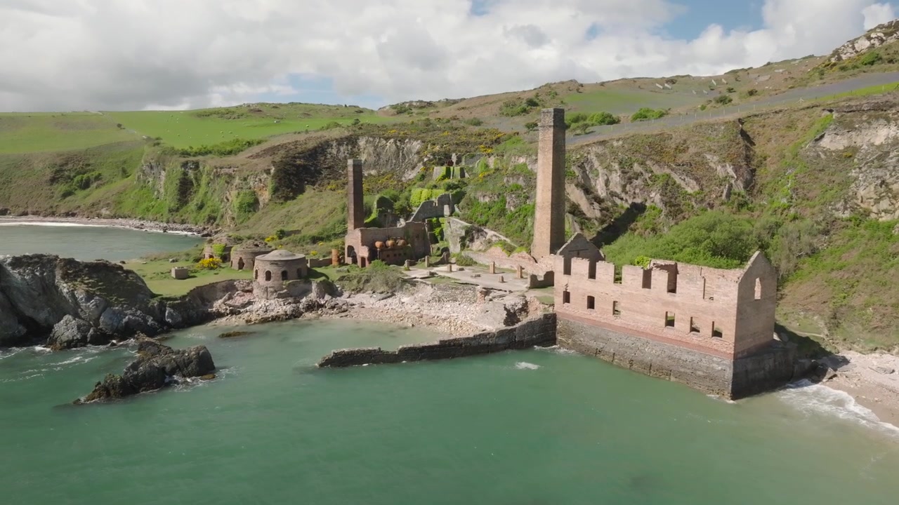 Porth Wen Brickworks, Anglesey, Wales. Langsom droneflyvning over havet mod forladte bygninger, ovne og skorstene