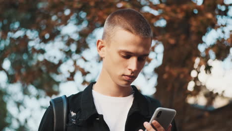 young student using mobile phone outdoors.