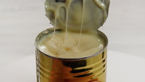 leche condensada con azúcar, abre una lata de un ingrediente cremoso, revelando con éxito su delicioso contenido dentro