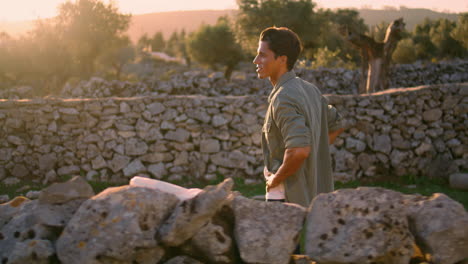 Calm-man-strolling-ancient-fence-landscape-side-view.-Guy-walking-alone-vertical