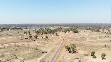 Amplia-Toma-Aérea-De-Tierra-árida-Y-árida-Con-Carretera-Asfaltada-Y-Agua-A-Distancia-En-La-Aldea-De-Charu-En-Chatra,-Jharkhand,-India