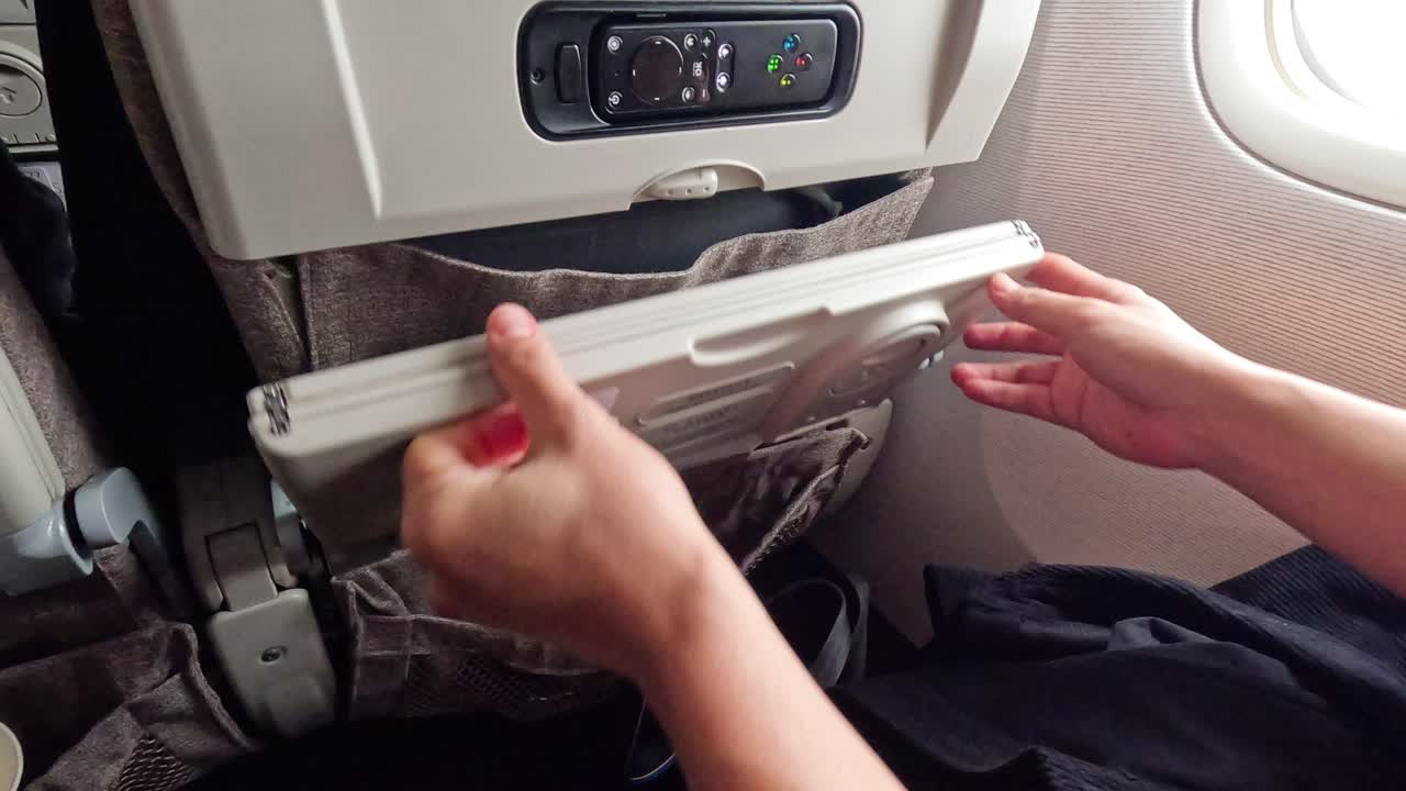 Passenger unfolds tray table on airplane seat