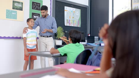teacher praises biracial boy in a classroom at school