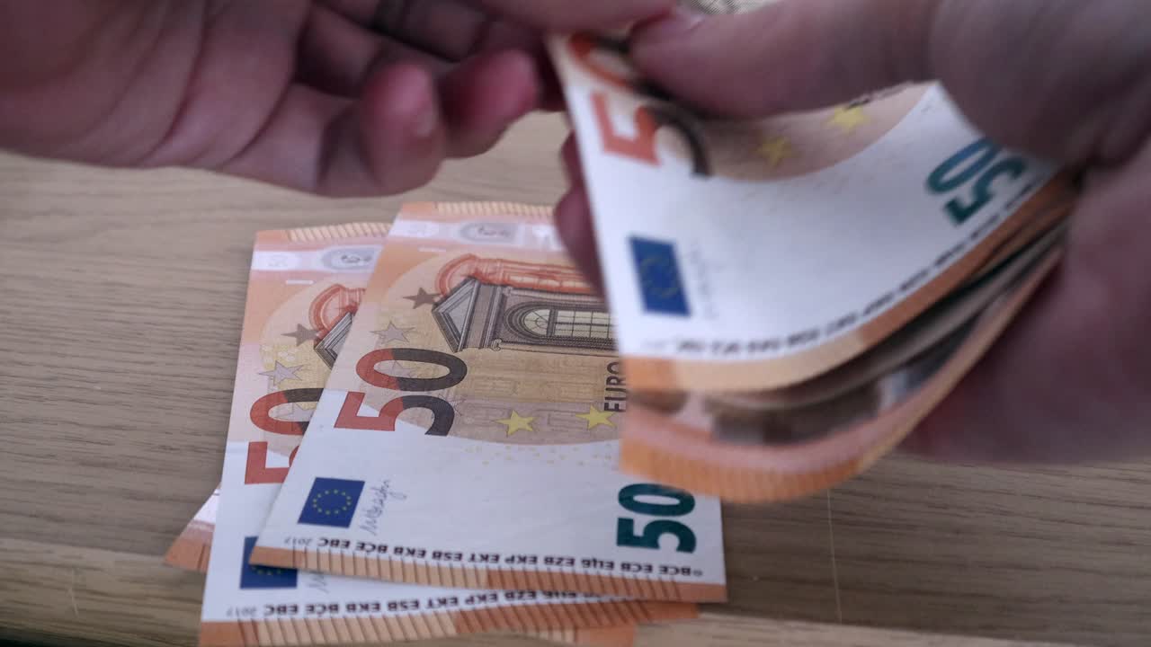 Close up shot of the hands of a rich man counting 50 euro bills or notes and keeping it on the table aside