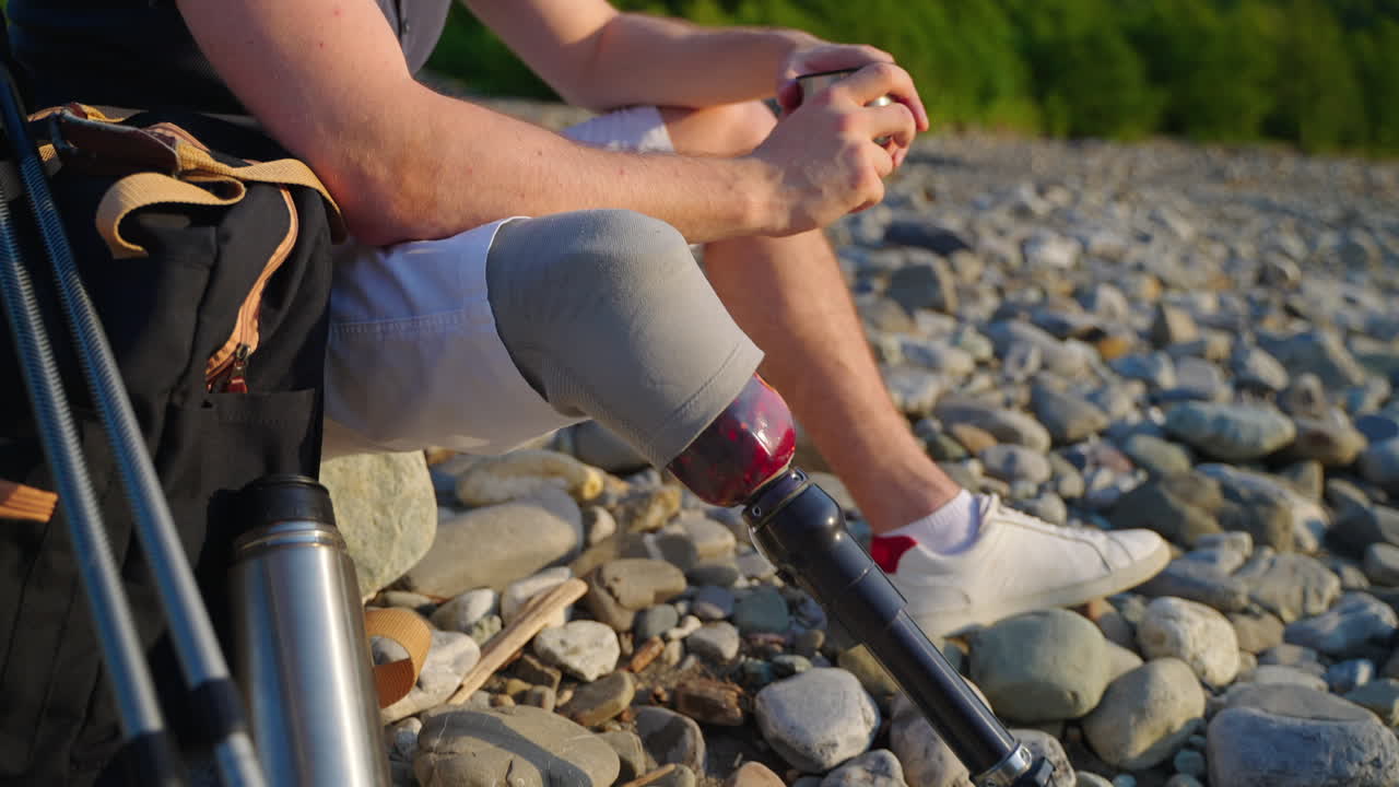 Person with a prosthetic leg resting by a river