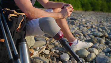 person with a prosthetic leg resting by a river