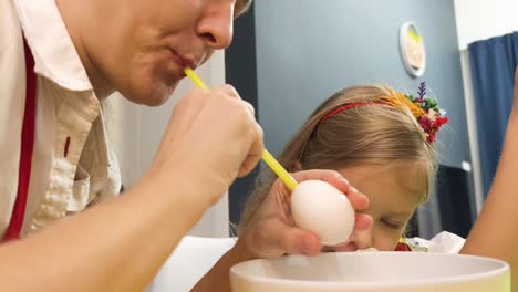 mother and daughter coloring easter eggs with straw