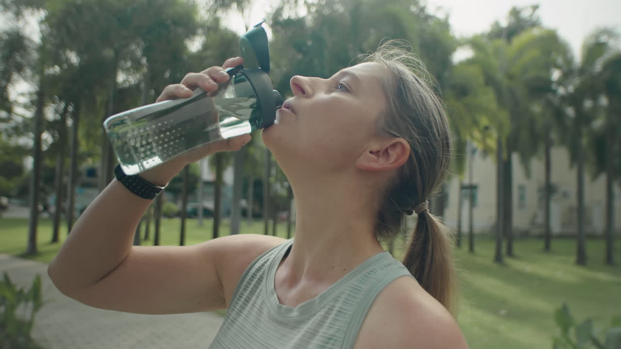 Woman Drinking Water after Workout in Park