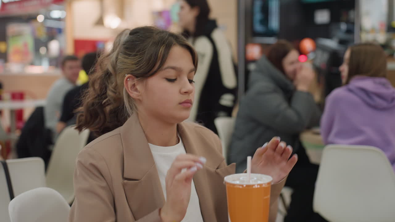 생각에 잠긴 여성이 식사하는 모습, 쇼핑몰에서 잠시 생각에 잠긴 소녀, 실내에서 혼자 밥을 먹으며 생각하는 젊은 여성, 붐비는 쇼핑몰 안에서 조용한 점심시간 동안 깊이 생각하는 젊은 여성