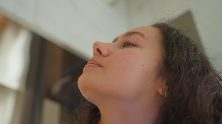 Primo piano di un ospite nel bagno dell'hotel che asciuga i capelli ricci allo specchio, con l'asciugamano avvolto. Asciugacapelli bianco portatile, luce solare soffusa, dita che massaggiano le radici. Atmosfera rilassata di cura personale nella toeletta di un boutique hotel con dettagli argentati.