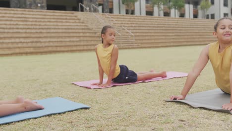 video de niñas diversas enfocadas practicando yoga en esteras frente a la escuela