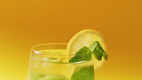 close up of drink with lemon on yellow background