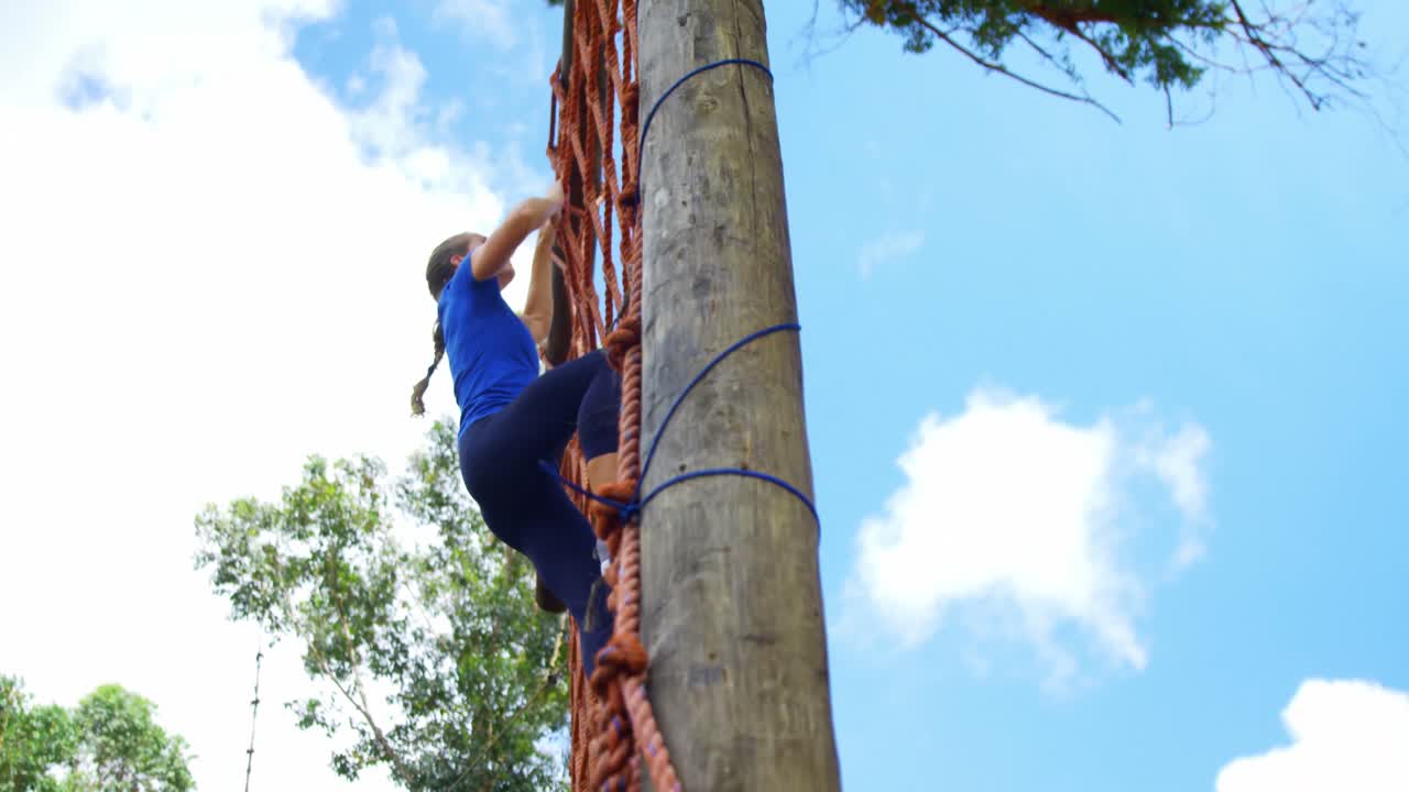 mujer subiendo una red durante el curso de obstáculos 4k