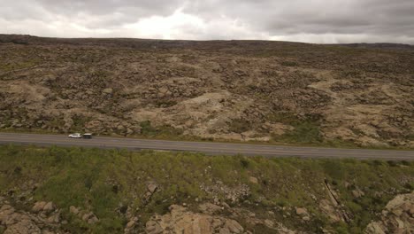 Toma-Aérea-De-Seguimiento-De-Un-Automóvil-En-La-Carretera-De-Las-Tierras-Altas-Con-Un-Remolque-De-Caja-Durante-Un-Día-Nublado-En-Argentina