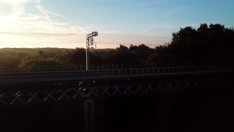 horizontal aerial following - ascending over railway bridge sunrise, early, frosty, misty morning