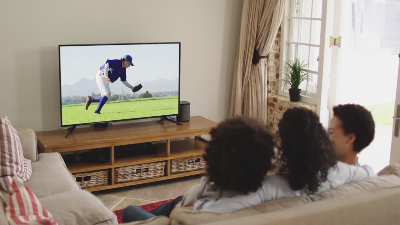 Famiglia felice seduta a casa insieme che guarda una partita di baseball in TV